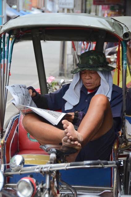 Tuk tuk driver reading news stories in Chiang Mai, Thailand