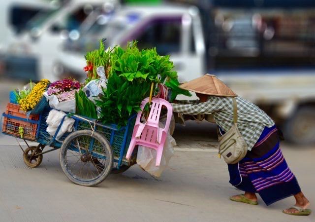 Woman pushing cart in Myanmar.